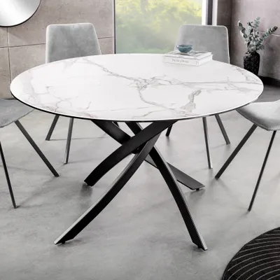 A round dining table with a marble-patterned top and a black metal base, surrounded by chairs in a dining room setting.