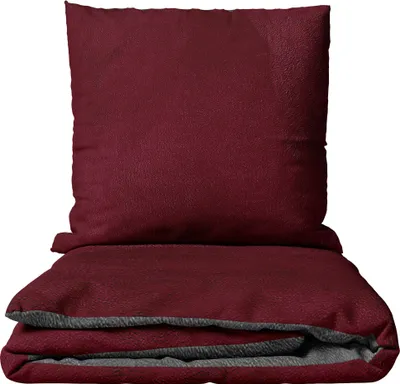 A folded burgundy duvet and pillow set on a white background.