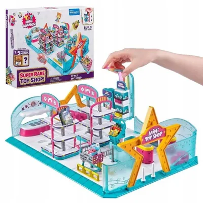 A toy shop playset with a box in the background and a hand interacting with the playset.