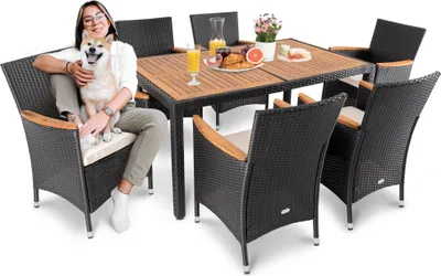 A woman and her dog are sitting on chairs around a table set for a meal.