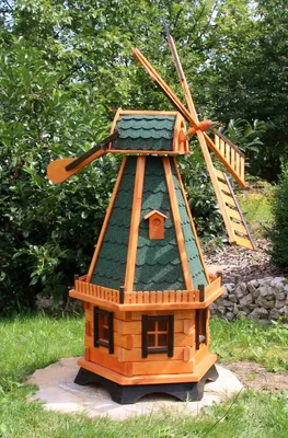 A wooden windmill decoration in a garden setting.