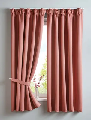 Two pink curtains are shown hanging in front of a window. One curtain is tied back with a fabric tie.