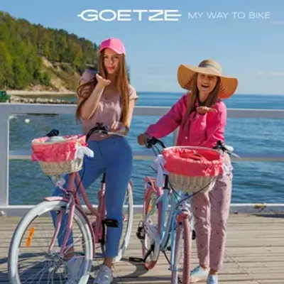 Two young women with bicycles on a wooden pier by the sea.