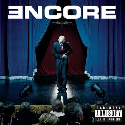 Eminem on stage in front of curtains, with an audience in the foreground.