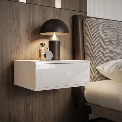 A bedside table with a lamp and two bottles on it, next to a bed.