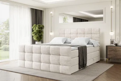 A bedroom scene featuring a large beige upholstered bed.