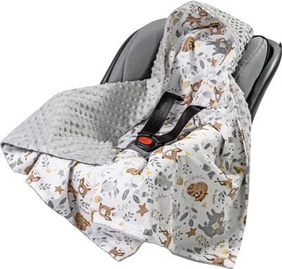 A baby blanket with a woodland animal print is draped over a car seat.