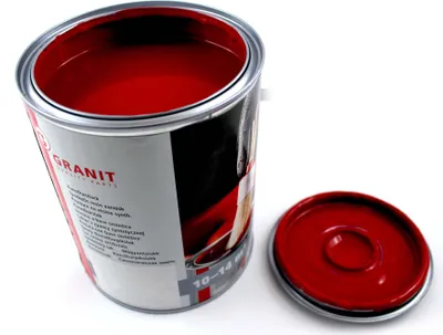 An open can of red paint with its lid next to it, on a white background.