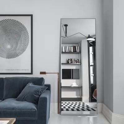 A modern living room with a blue sofa, a large framed poster, and a tall floor mirror reflecting a bookshelf and a checkered rug.