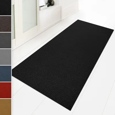 A black runner mat is shown on a white floor in front of a white cabinet.