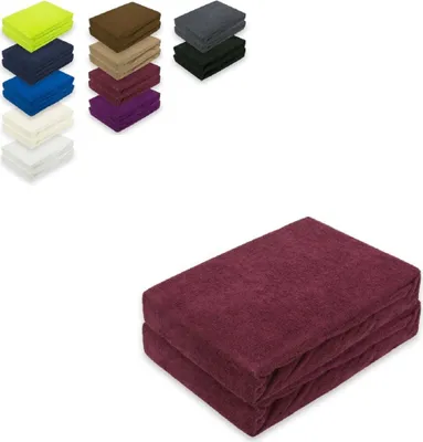A stack of folded burgundy towels is shown in the foreground, with smaller stacks of towels in various colors displayed in the background.