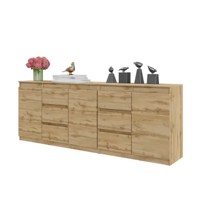 A long, light wood sideboard with multiple drawers and doors, decorated with a vase of pink flowers and several bird figurines.
