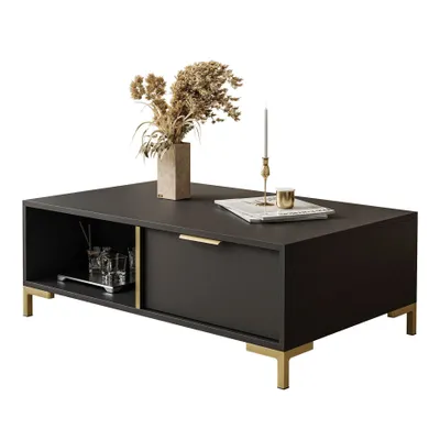 A dark gray coffee table with gold legs and a gold drawer pull, decorated with a vase of dried flowers, a candlestick, and a book.