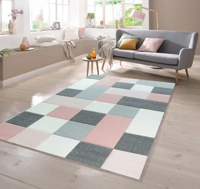 A modern living room with a sofa, coffee table, and a geometric patterned rug.