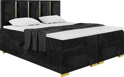 A black upholstered boxspring bed with gold accents and white bedding.