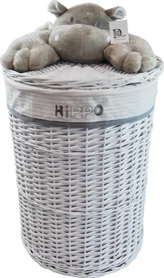 A white wicker laundry basket with a plush hippo toy on top.