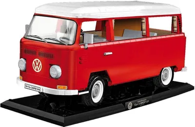 A red and white Volkswagen Transporter T2A camper van model on a black display stand.