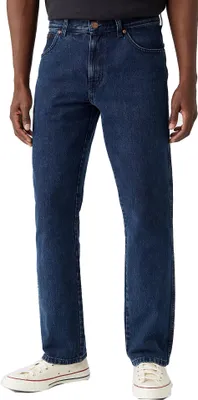 A person wearing dark blue jeans and white sneakers, shown from the waist down against a white background.