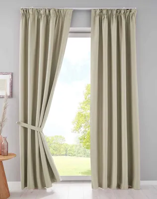 A pair of beige curtains are shown hanging in front of a window, with one curtain tied back.