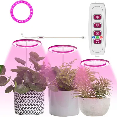 Three potted plants are shown under LED grow lights, with a remote control nearby.