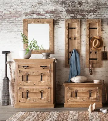 A hallway set with a mirror, chest of drawers, and coat racks against a brick wall.