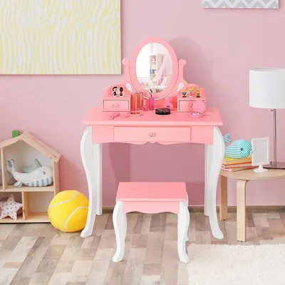 A pink children's vanity table and stool set with a mirror, placed in a room with pink walls and wooden flooring.