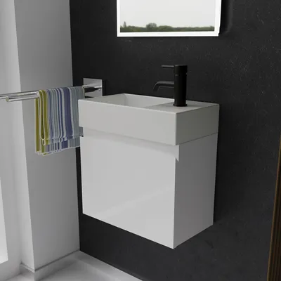 A modern bathroom vanity with a white sink and cabinet, a black faucet, and a towel rack with colorful towels.