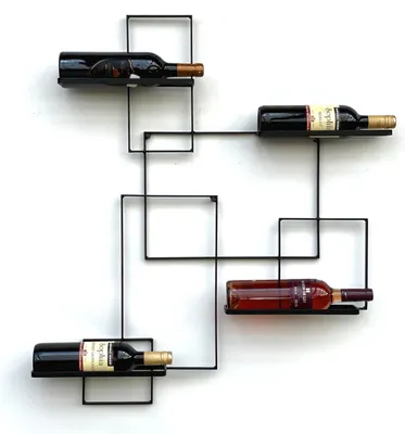 A black metal wine rack mounted on a white wall, holding four bottles of wine.