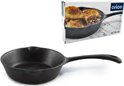 A cast iron frying pan is shown in front of its packaging.