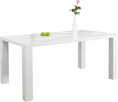 A white dining table with a vase of flowers and two green apples on a plate.