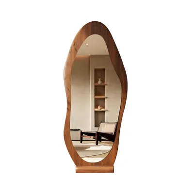 A full-length mirror with an irregular wooden frame, reflecting a room with a chair and shelves.