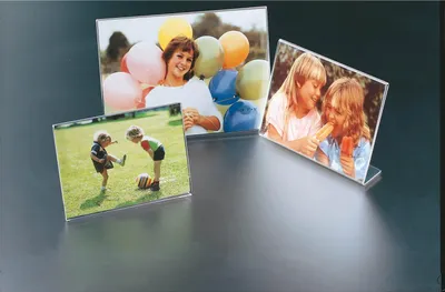 Three acrylic photo frames with different photos are displayed on a reflective surface.