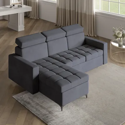 A modern living room with a gray sectional sofa, a white desk, and a round gold coffee table with a vase of flowers.