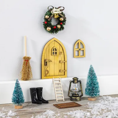A collection of miniature Christmas-themed items arranged on a white surface against a white wall.