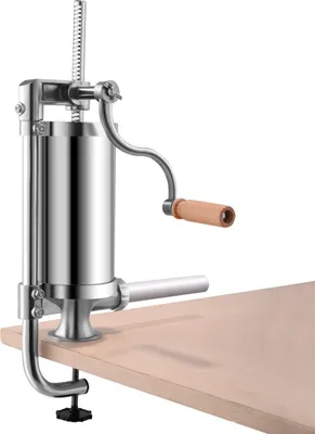 A metal sausage stuffer clamped to a wooden surface against a white background.