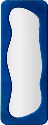 A full-length mirror with an irregular-shaped white reflective surface and a blue velvet frame.