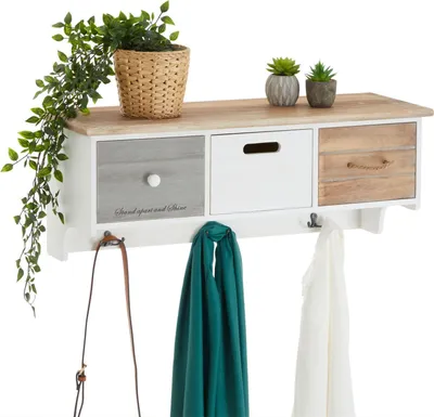 A white wall-mounted shelf with three drawers and hooks, decorated with plants and scarves.