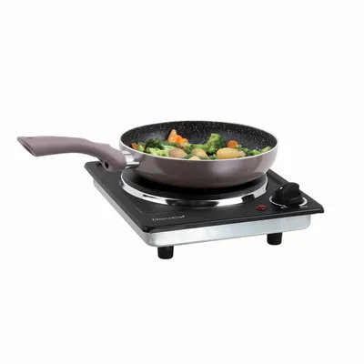 A portable electric cooktop with a frying pan containing vegetables.