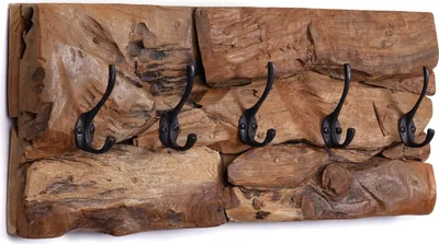 A wooden coat rack with five black metal hooks mounted on a textured wooden panel.