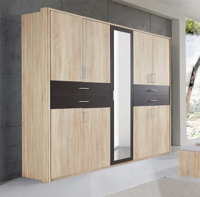 A large wardrobe with a mirrored door, set against a gray wall and a window with a view of trees.