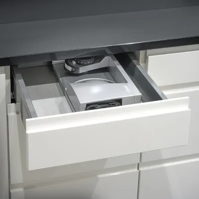 A close-up view of a kitchen drawer with a compact appliance inside.