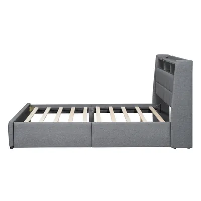 A side view of a grey upholstered bed frame with a slatted mattress support.