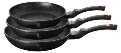 Three black frying pans stacked on top of each other against a white background.