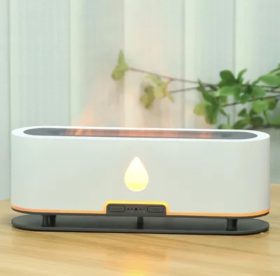 A white aroma diffuser with a flame-like light effect sits on a wooden table.