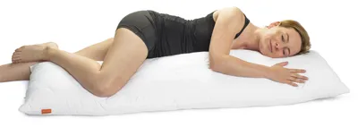 A woman is sleeping on a long white pillow.