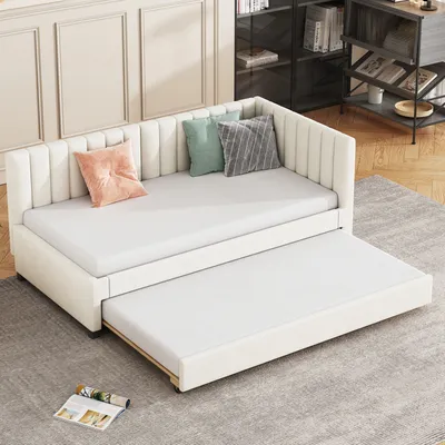 A beige daybed with an extended trundle bed, set up in a room with a bookshelf in the background.