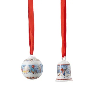 Two Christmas ornaments, a ball and a bell, hanging from red ribbons against a white background.