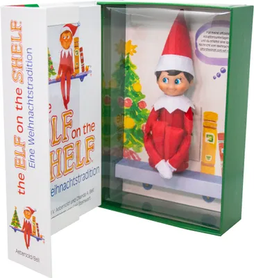 The Elf on the Shelf box set, showing the elf doll inside its packaging with a Christmas tree and books.