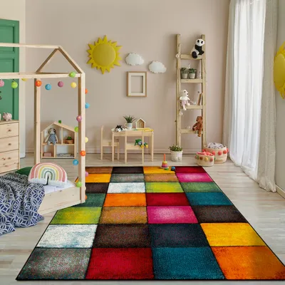 A child's bedroom with a bed, a small table and chairs, and a colorful rug.