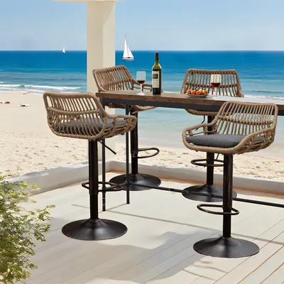 Bar stools and a table on a deck overlooking a beach and the ocean.
